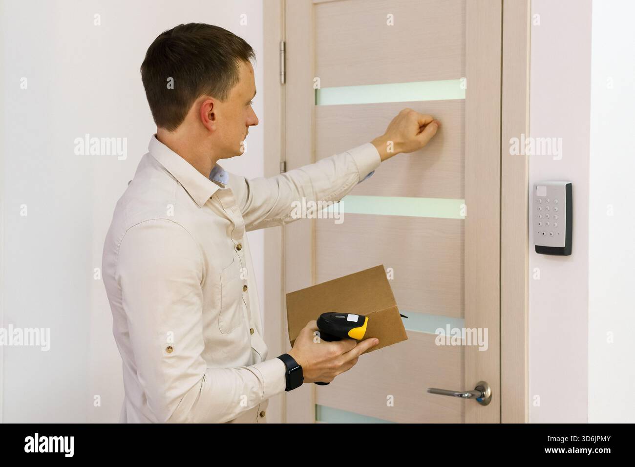 Seitliche Ansicht des Mitarbeiters bei der Auftragsabholung, der mit Paket- und Strichcodeleser an die Tür klopft Stockfoto