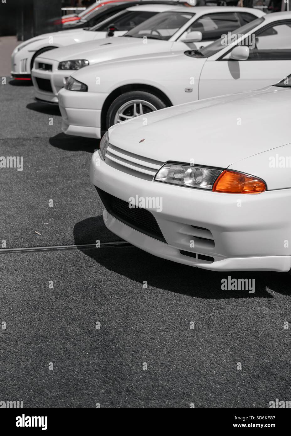 Vier Nissan Skyline GT-RS verschiedener Generationen. Vertikales Bild von Nissan-Autos der 1990er-2000er-Jahre an einem sonnigen Tag auf dem Parkplatz. Stockfoto