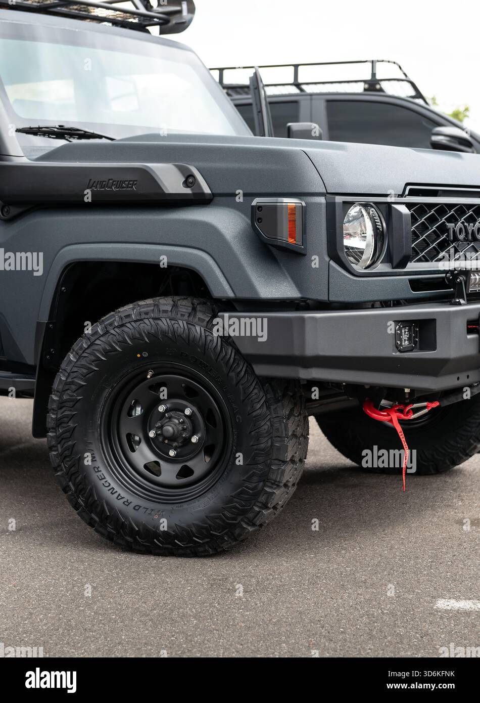 Vorderansicht des kundenspezifischen Land Cruiser 70. Robuster, dunkelgrauer Toyota SUV mit Raptorbeschichtung, Geländereifen auf Stahlfelgen und robustem Stoßfänger. Stockfoto