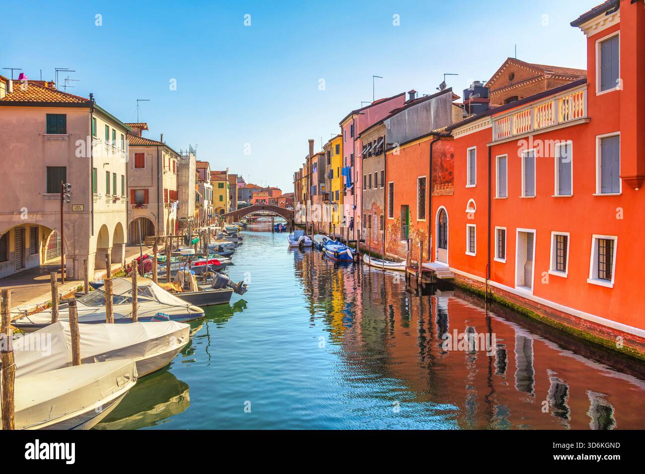 Lebhafter Blick auf den Vena Canal in Chioggia, bekannt als Little Venice. Traditionelle, farbenfrohe Häuser säumen das Wasser und eine Brücke ist in der Ferne sichtbar Stockfoto