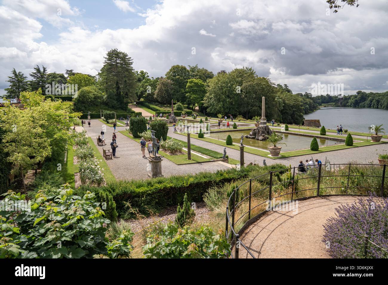 Woodstock, Vereinigtes Königreich, 12. Juli 2023, strukturierte Pfade und getrimmte Hedges führen leise zum See. Weiches Licht filtert durch die Wolkenerzeugung Stockfoto