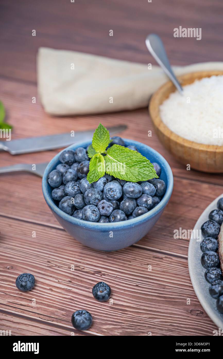 Die Wärme der Gold- und Brauntöne des Natur lackierten Holzes verstärkt die Frische und kühle Farbe der frisch geernteten Heidelbeeren Stockfoto