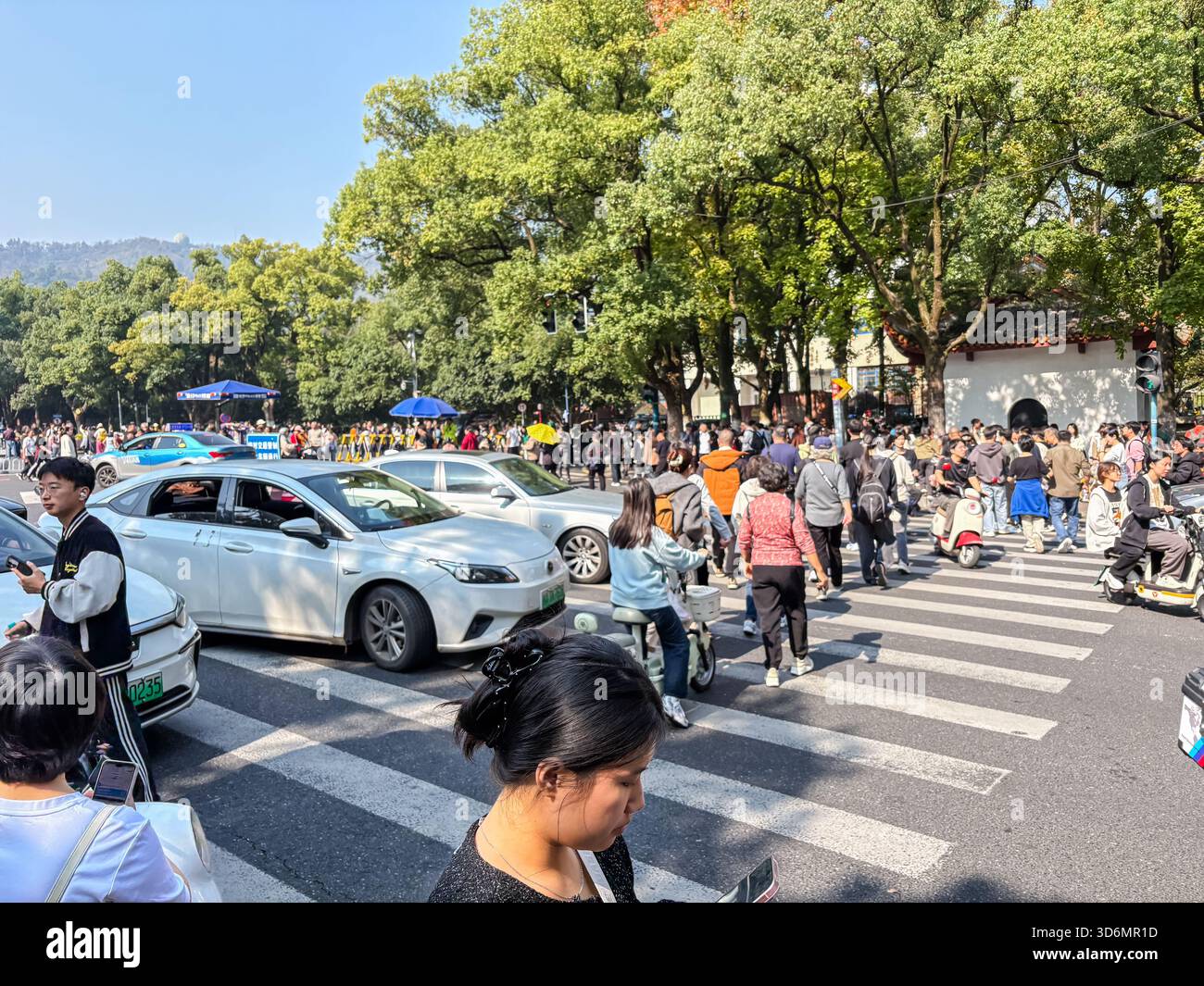 Eine geschäftige und überfüllte Straßenszene in Changsha, China, mit zahlreichen Autos, Rollern und Fußgängern, die an einer geschäftigen Kreuzung in der Nähe der Hunan Unive vorbeifahren Stockfoto