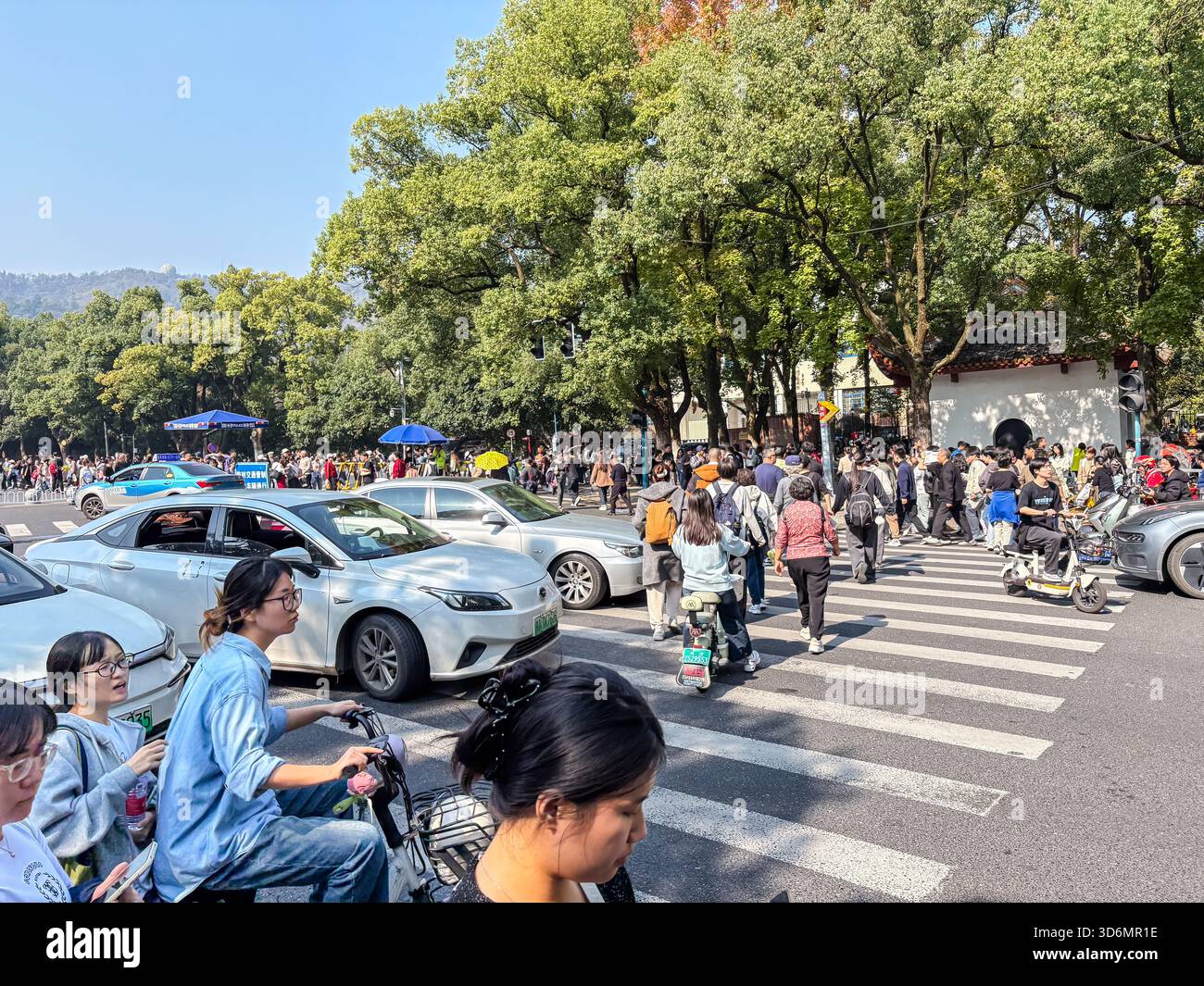 Eine geschäftige urbane Straßenszene in Changsha, China, mit vielen Fußgängern, die eine Straße voller Autos überqueren, und Menschen in der Nähe der Hunan University, die täglich zeigen Stockfoto