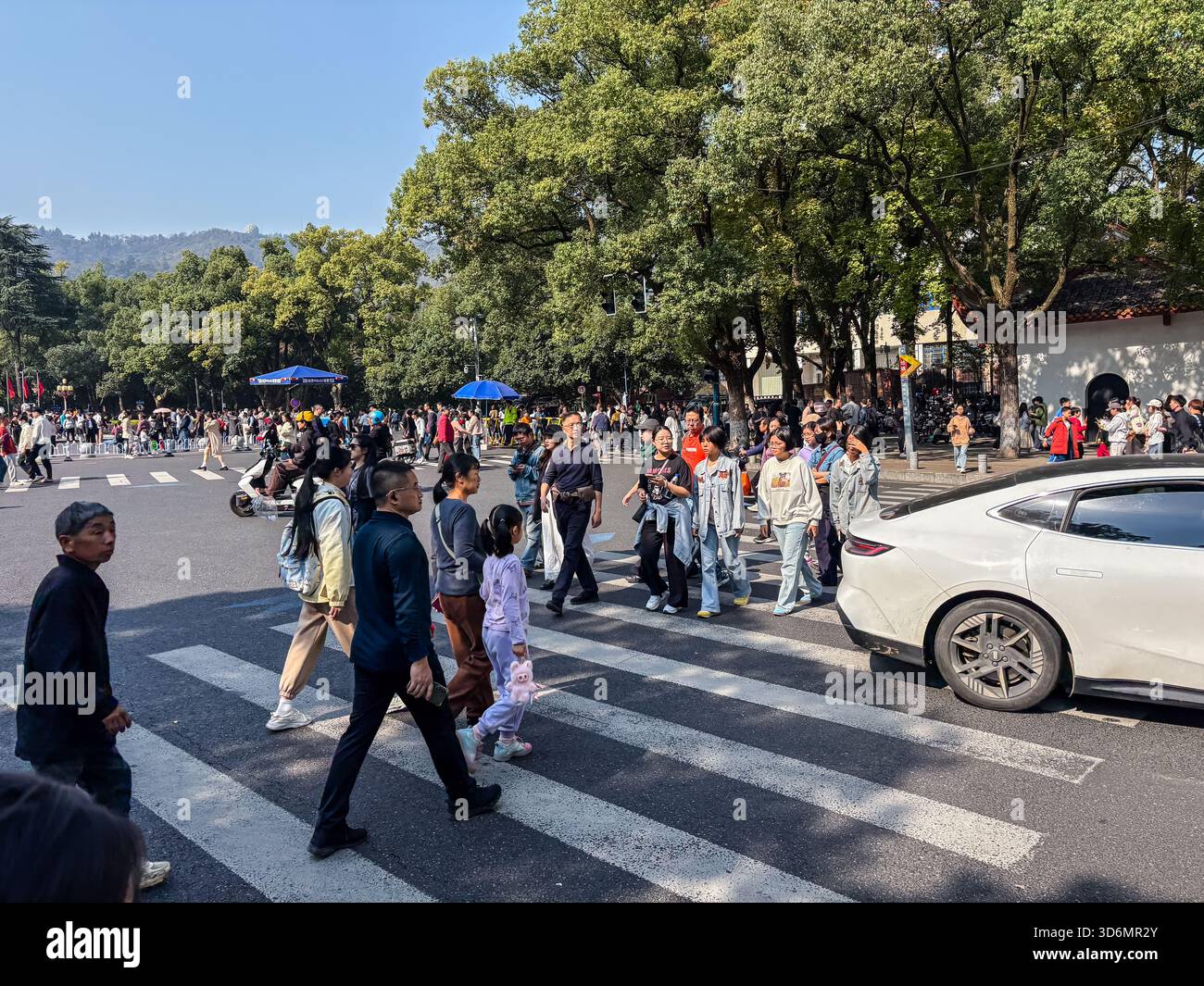 Überfüllte Straße mit vielen Fußgängern, die eine Kreuzung überqueren und Autos warten, in der Nähe der Hunan University in Changsha, China. Zeigt urbanes Leben und Verkehr c Stockfoto
