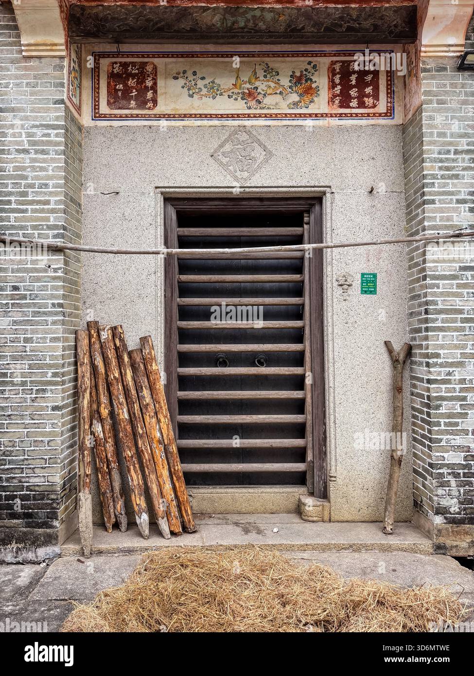 Traditioneller Eingang, Zili Village. Historische Tür mit Holzlatten, dekorativem Fries und traditionellen Gegenständen an der Basis. Kaiping, Chin Stockfoto