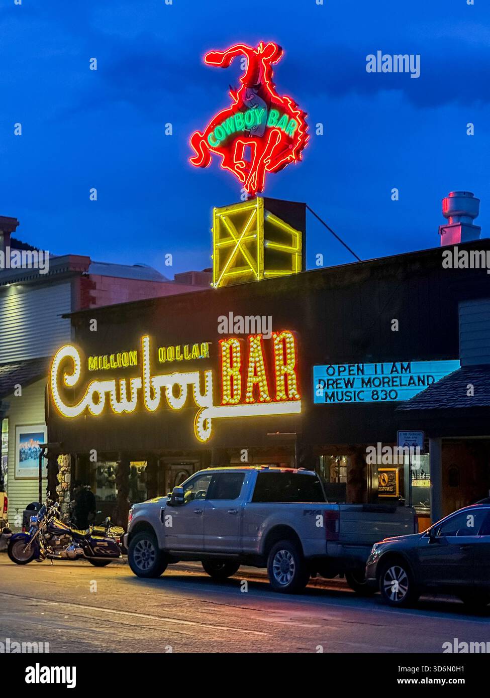 Neonlichter beleuchten die Million Dollar Cowboy Bar in Jackson, Wyoming. Die ikonische Beschilderung eines roten Neonbocks und einer leuchtenden „Cowboy Bar“ Stockfoto