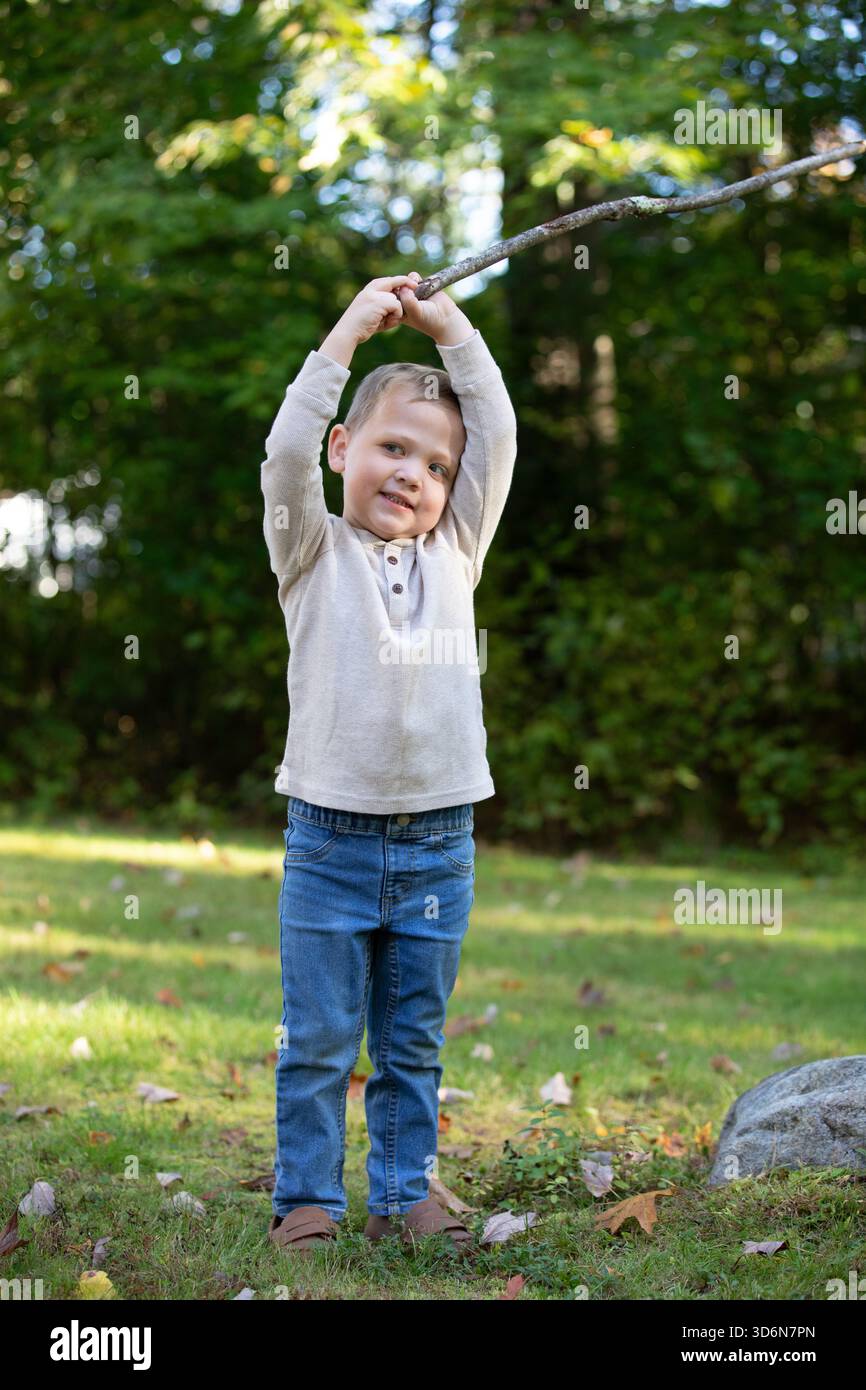 Blonder, blauäugiger Junge, der einen Stock hält Stockfoto