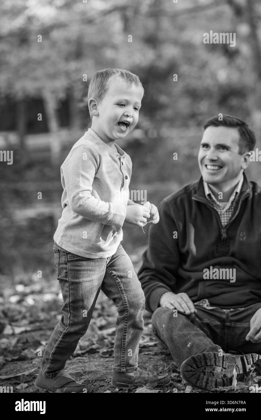Ein Junge läuft vor Freude, während sein fröhlicher Vater zusieht Stockfoto