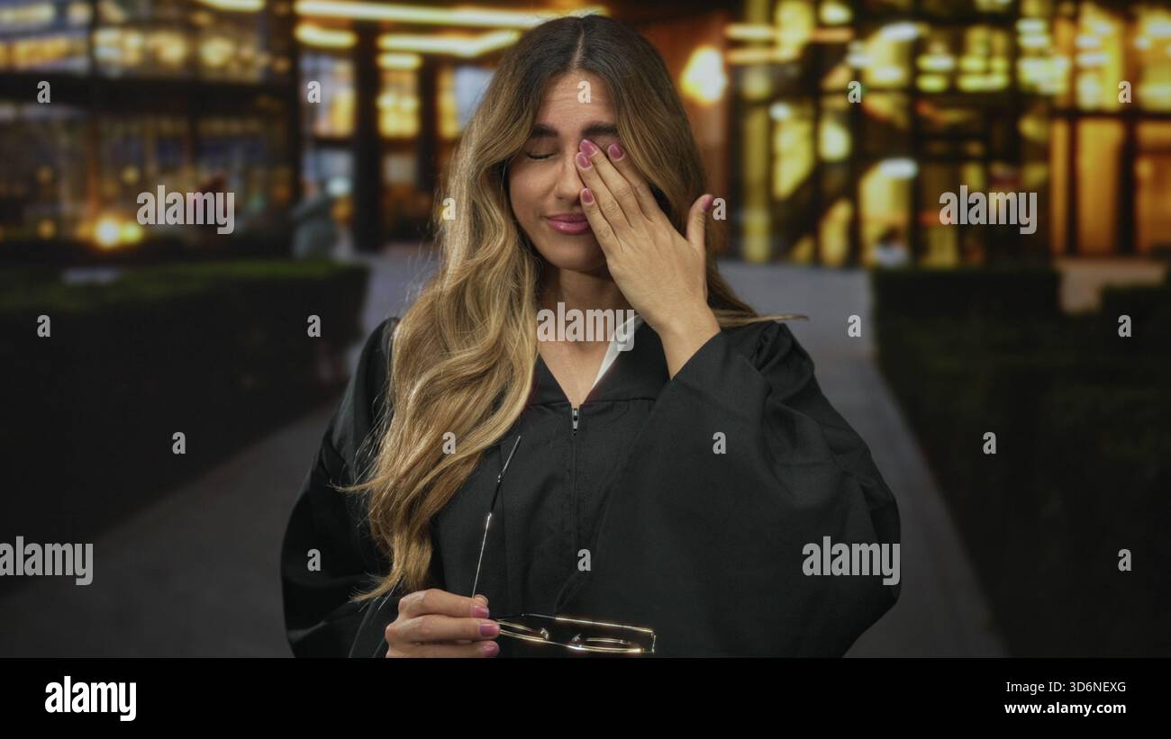 Richterin in Robe drückt den Finger an die Lippen, um nachts im beleuchteten Innenhof Ruhe zu verschaffen; Geheimhaltung der Autorität. Stockfoto