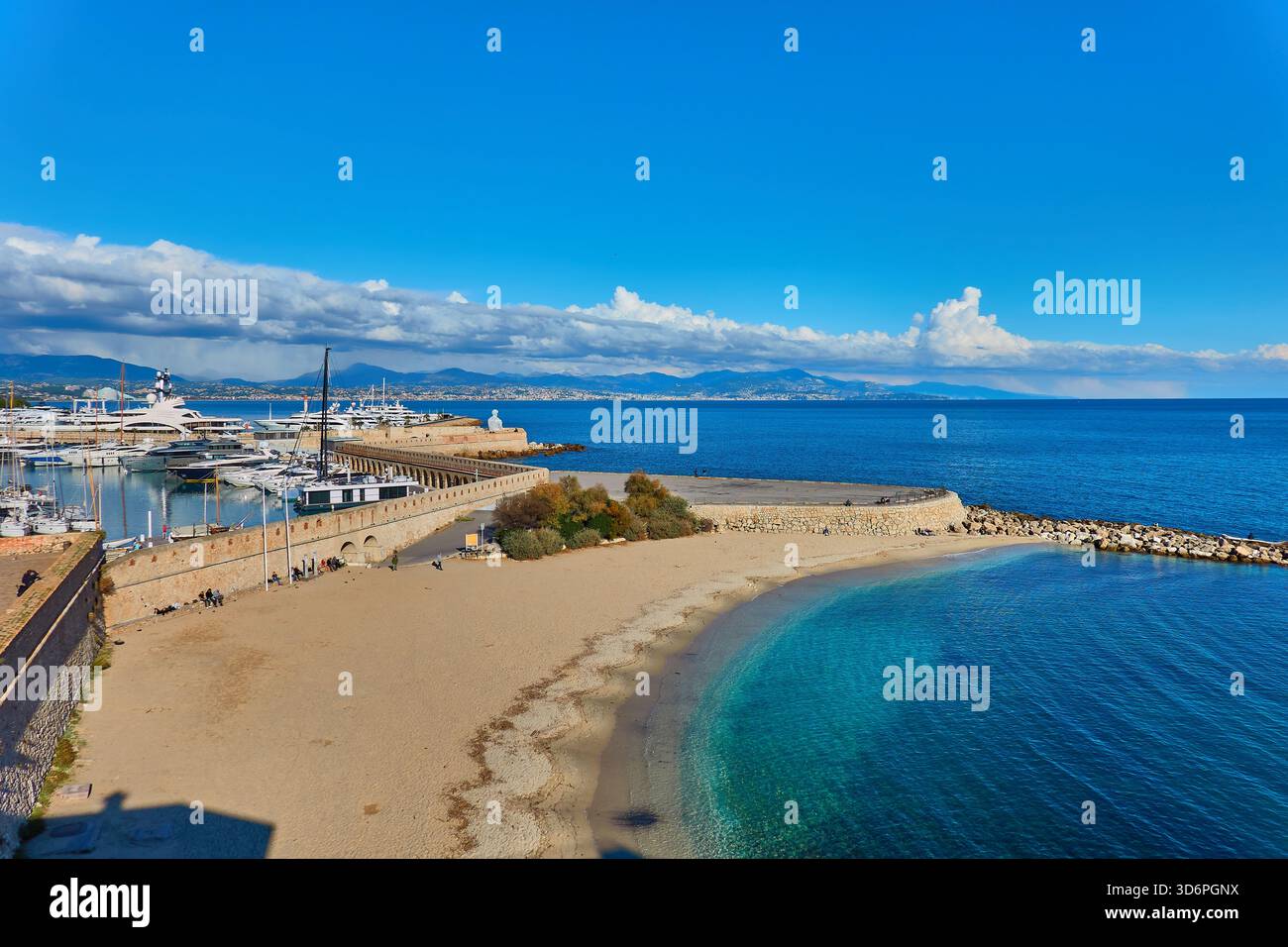 Sonniger Hafen am Meer mit Booten, Strand, weichem Sand, kristallklarem blauem Wasser und Blick auf die Küste Stockfoto