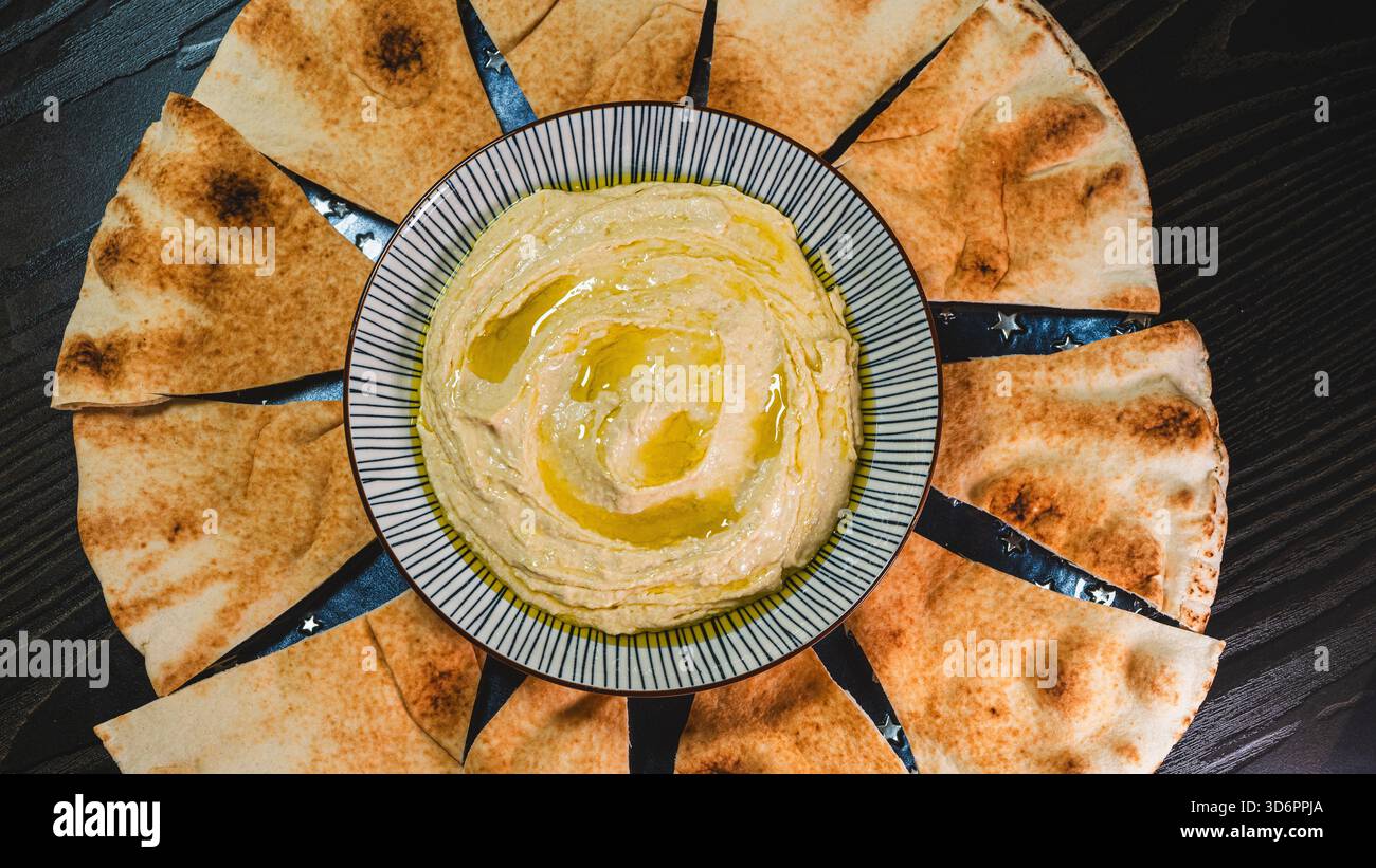 Hausgemachter Hummus in einer Schüssel, mit Olivenöl getränkt und mit Paprika bestreut. Perfekt als Dip oder Aufstrich, servierfertig. Authentisches Middle Easte Stockfoto