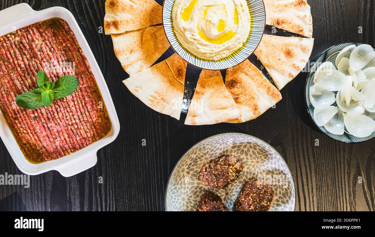 Komplettieren Sie das Mezze aus dem Nahen Osten mit frittiertem Kibbeh, Kibbeh Nayeh und Hummus in separaten Gerichten. Perfekt zum Teilen und für authentische kulinarische Präsentationen Stockfoto