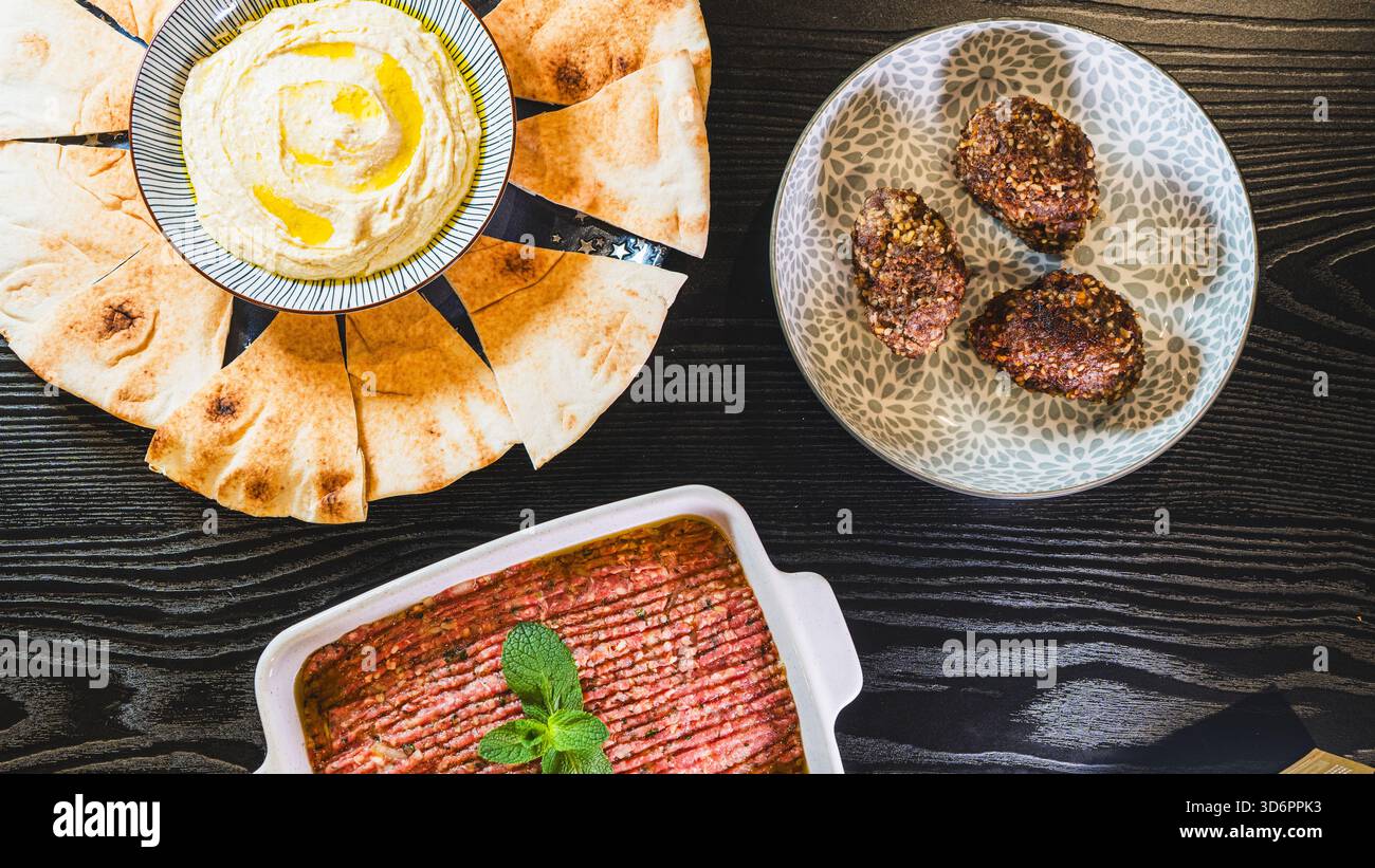Komplettieren Sie das Mezze aus dem Nahen Osten mit frittiertem Kibbeh, Kibbeh Nayeh und Hummus in separaten Gerichten. Perfekt zum Teilen und für authentische kulinarische Präsentationen Stockfoto
