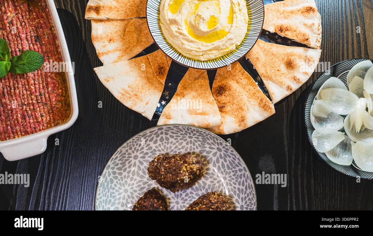 Komplettieren Sie das Mezze aus dem Nahen Osten mit frittiertem Kibbeh, Kibbeh Nayeh und Hummus in separaten Gerichten. Perfekt zum Teilen und für authentische kulinarische Präsentationen Stockfoto