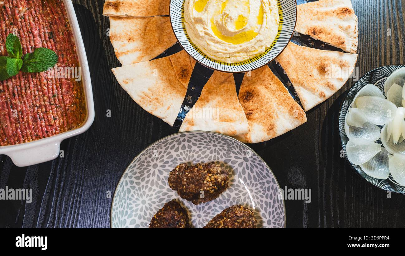 Komplettieren Sie das Mezze aus dem Nahen Osten mit frittiertem Kibbeh, Kibbeh Nayeh und Hummus in separaten Gerichten. Perfekt zum Teilen und für authentische kulinarische Präsentationen. Stockfoto