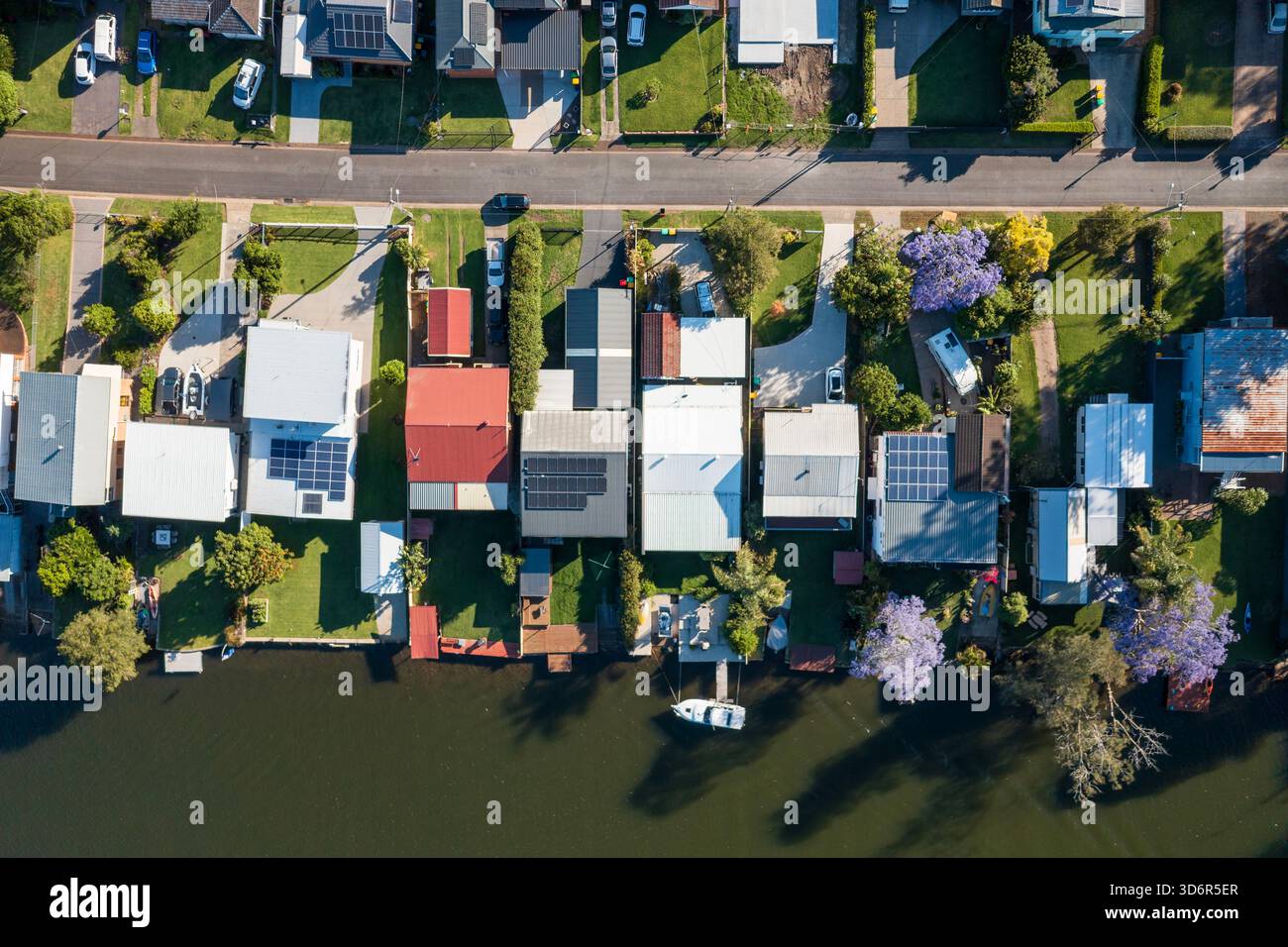 Blick von oben auf blühende Jacarandas, Gärten und Häuser mit privaten Slipways entlang des Dora Creek in der Region Lake Macquarie, NSW, Australien. Stockfoto