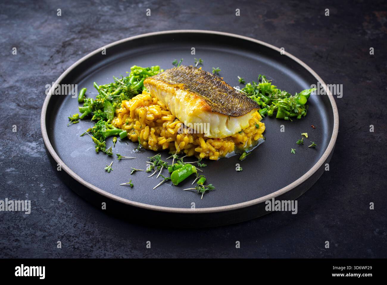 Gebratenes Fischfilet aus nordischem Kabeljau mit safran-Risottoreis, grünem Gemüse Stockfoto