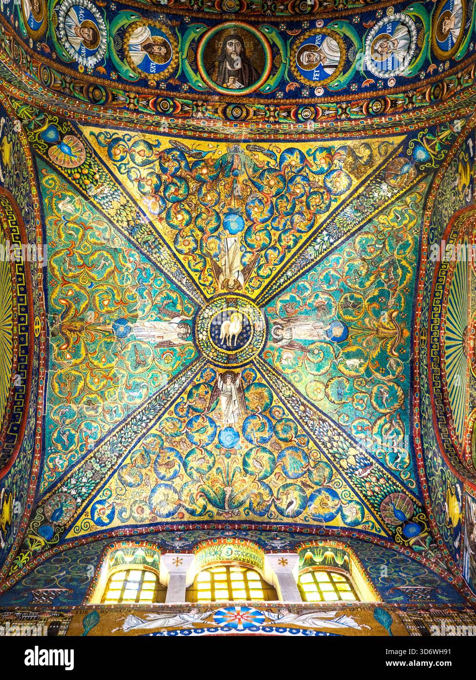 Das Kreuzrippengewölbe im Presbyterium ist reich mit Mosaiken aus Blättern, Früchten und Blumen verziert, die auf einer Krone zusammenlaufen, die das Lamm Gottes umgibt. Die Krone wird von vier Engeln gestützt, und jede Oberfläche ist mit einer Fülle von Blumen, Sternen, Vögeln und Tieren bedeckt, darunter viele Pfauen - Basilika San Vitale - Ravenna, Italien Stockfoto