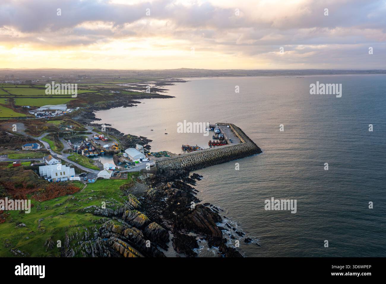 Blick aus der Vogelperspektive auf Port Oriel in Clogherhead mit Fischerbooten und trübem Abendlicht entlang der ruhigen Küste Stockfoto