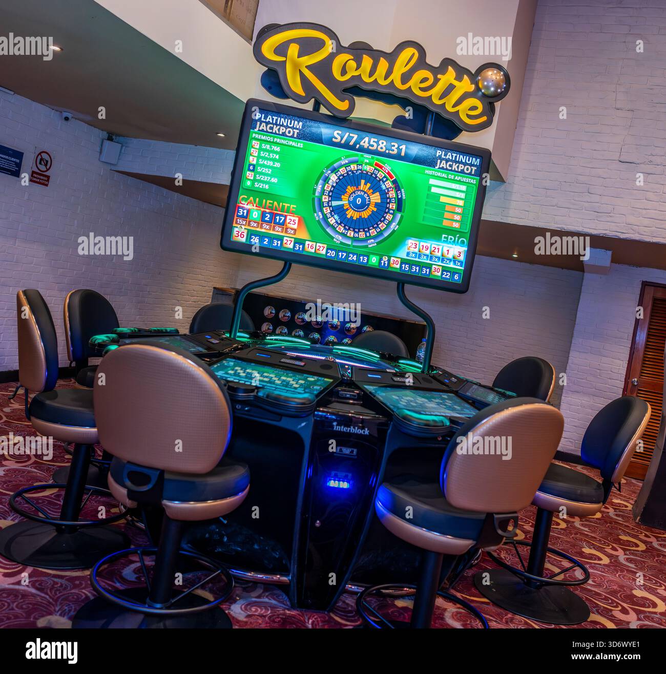 Moderner elektronischer Roulette-Tisch mit digitalem Jackpot-Bildschirm und Sitzplätzen im Casino-Innenraum, ideal für Spiele, Wetten und Unterhaltung. Stockfoto