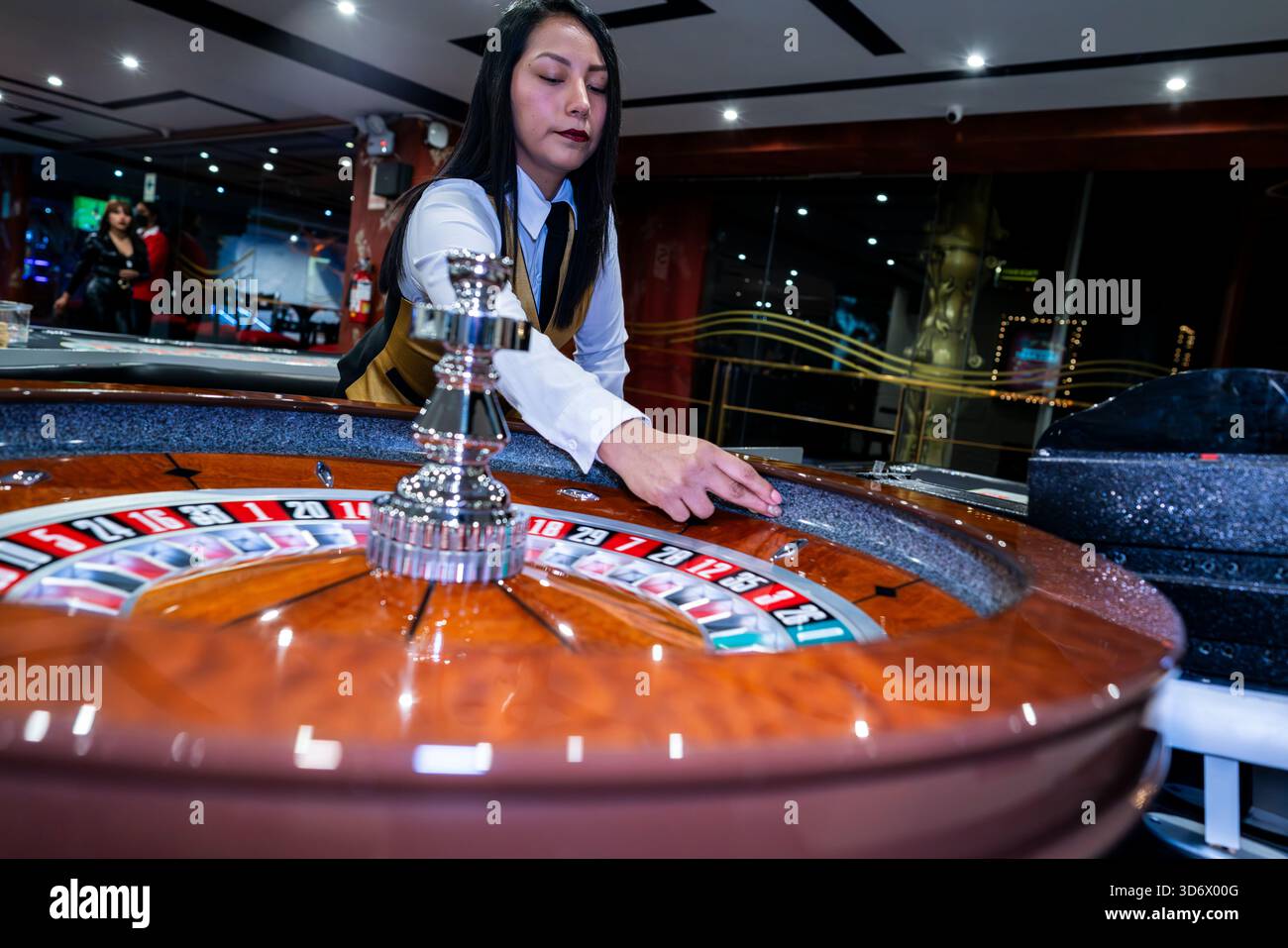 Croupier verwaltet Roulette-Rad im hellen Casino-Innenraum und zeigt Glücksspiel-, Wetten-, Risiko-, Glück- und Spielatmosphäre. Stockfoto