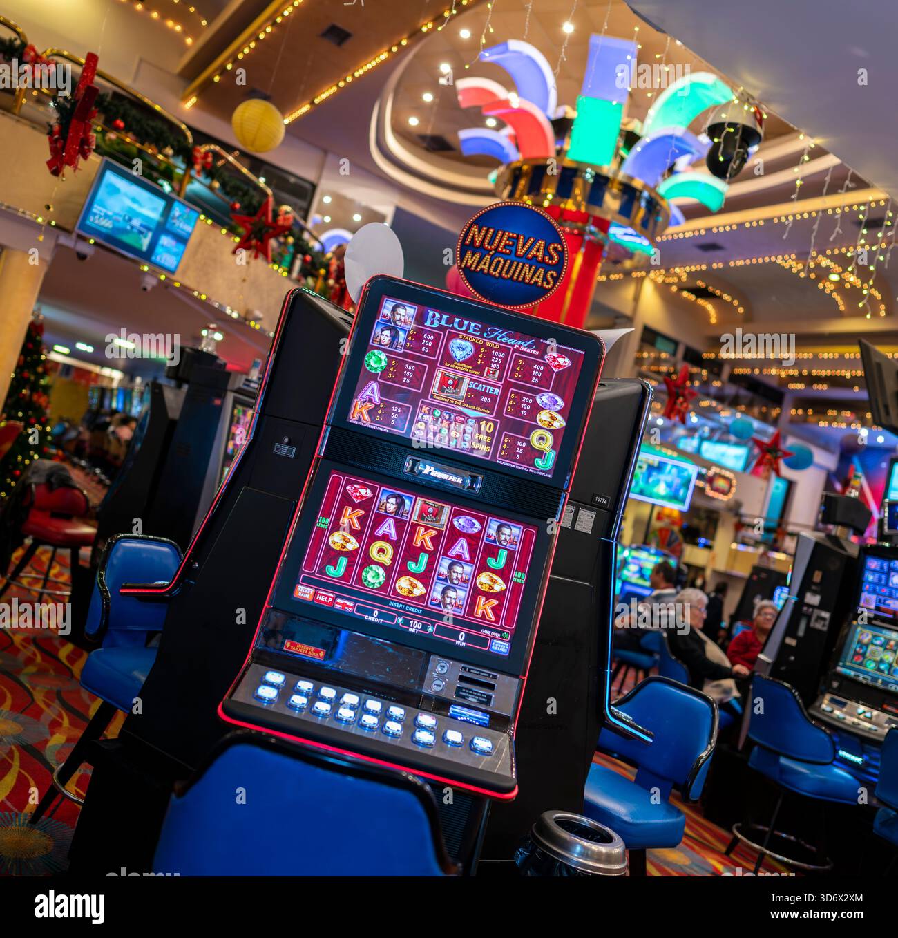Farbenfroher Spielautomat mit hellem Digitalbildschirm und festlicher Beleuchtung in einer aktiven Spielhalle, ideal für Glücksspiel- und Unterhaltungsthemen. Stockfoto