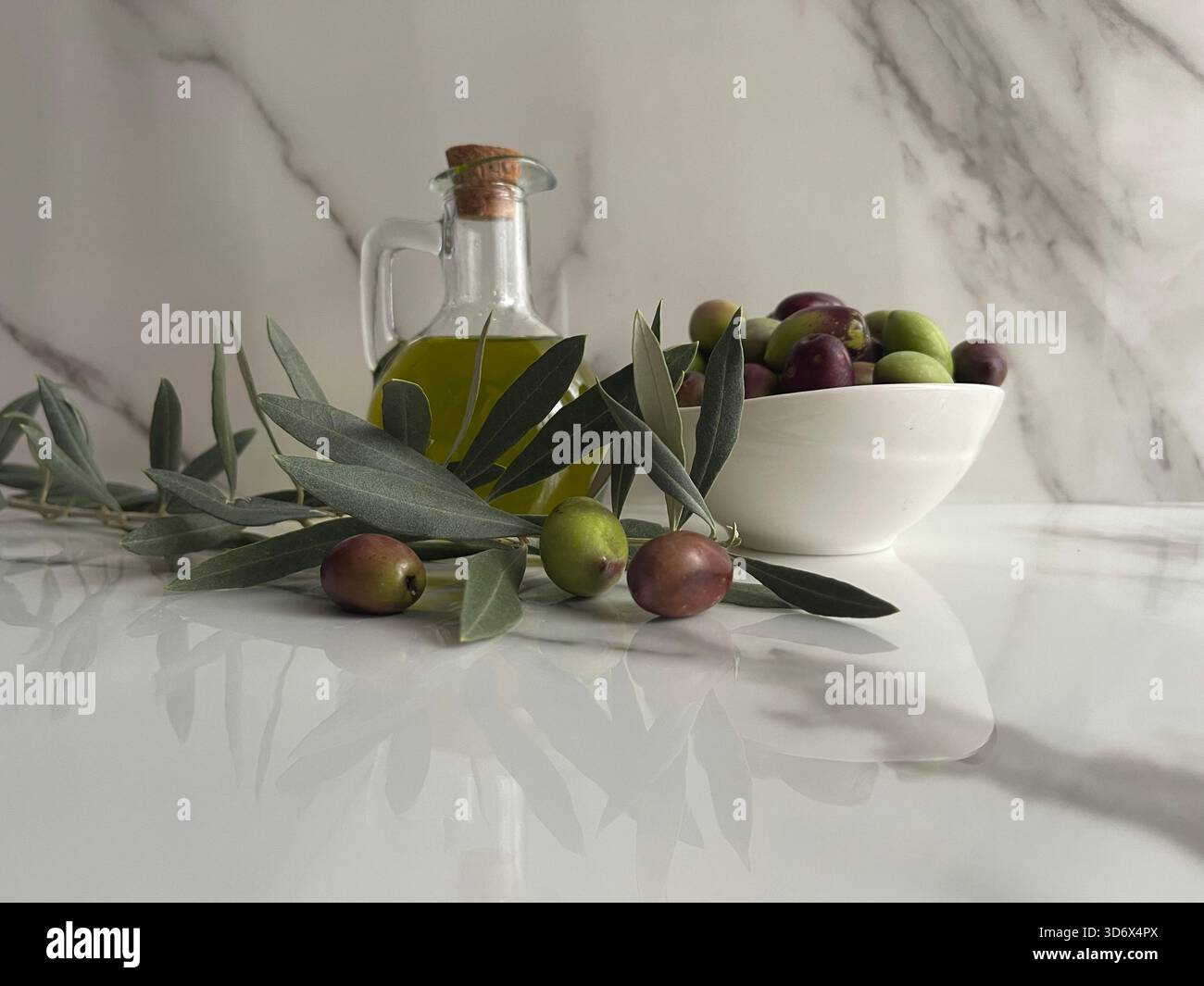Natürliches, umweltfreundliches Olivenöl in Griechenland mit einer Flasche und einem kleinen Gericht, umgeben von frischen grünen und schwarzen Oliven auf dem Tisch. - Smartphone-aufgenommenes Stockfoto