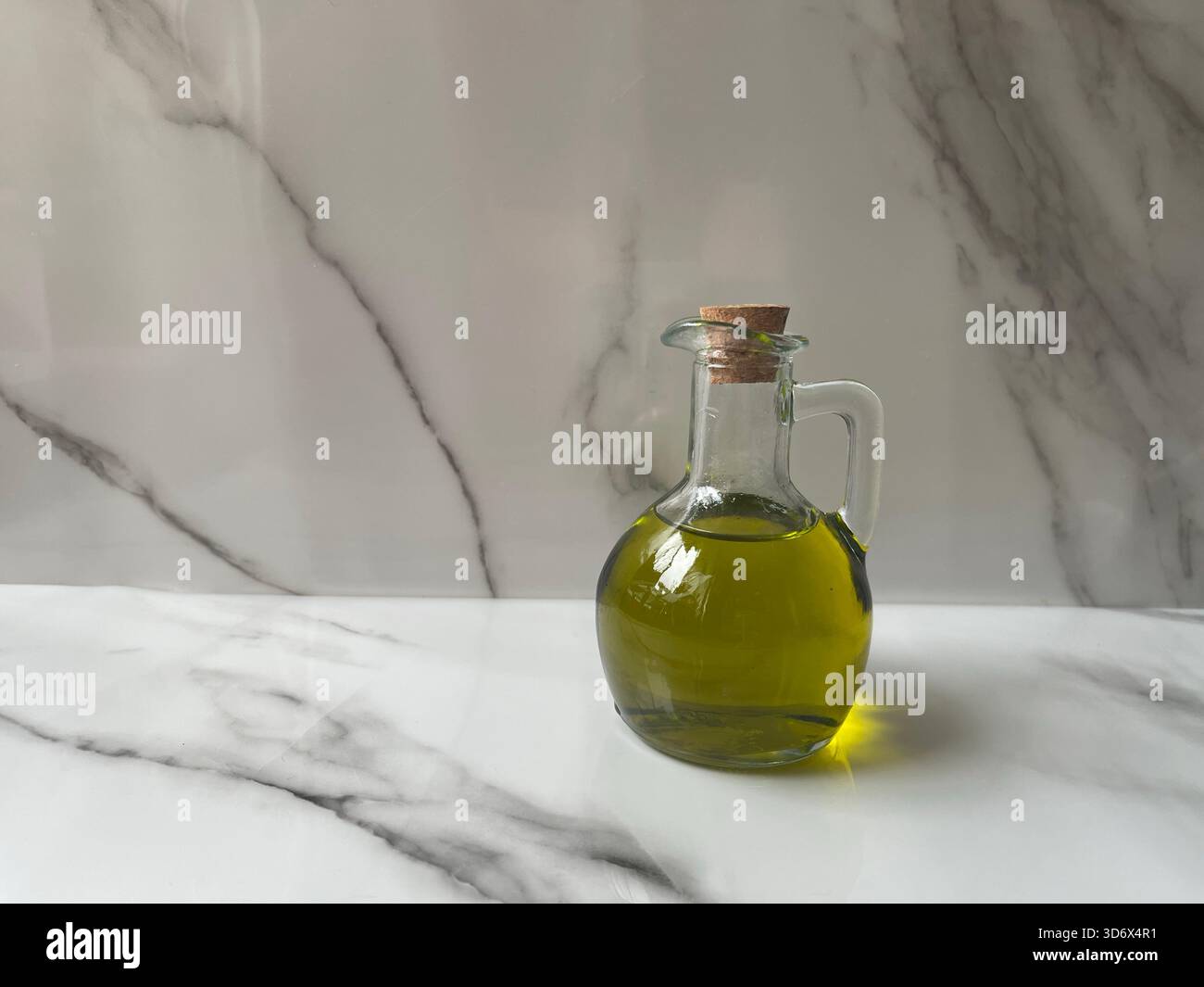 Natürliches, umweltfreundliches Olivenöl in Griechenland in einer Glasflasche auf dem Tisch, satte grüne Farbe, mit frischen Oliven in der Nähe, elegant und rustikal. - Smartphone-aufgenommenes Stockfoto