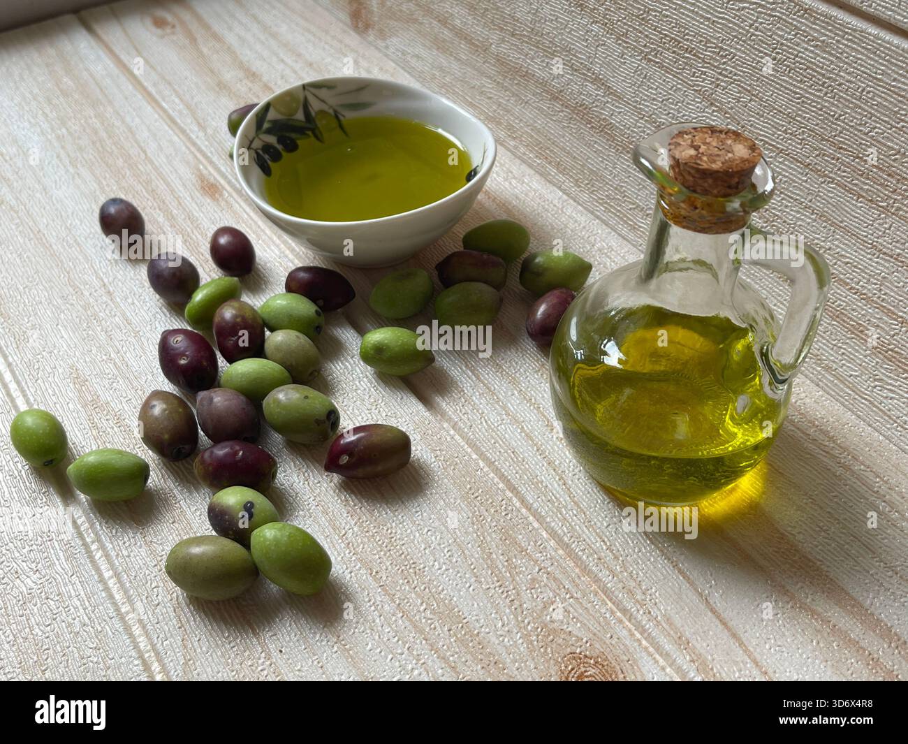 Natürliches, umweltfreundliches Olivenöl in Griechenland mit einer Flasche und einem kleinen Gericht, umgeben von frischen grünen und schwarzen Oliven auf dem Tisch. - Smartphone-aufgenommenes Stockfoto
