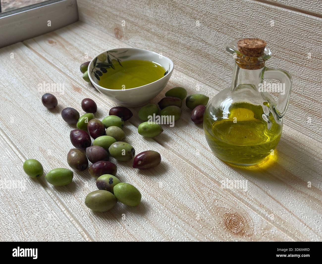 Natürliches, umweltfreundliches Olivenöl in Griechenland mit einer Flasche und einem kleinen Gericht, umgeben von frischen grünen und schwarzen Oliven auf dem Tisch. Stockfoto