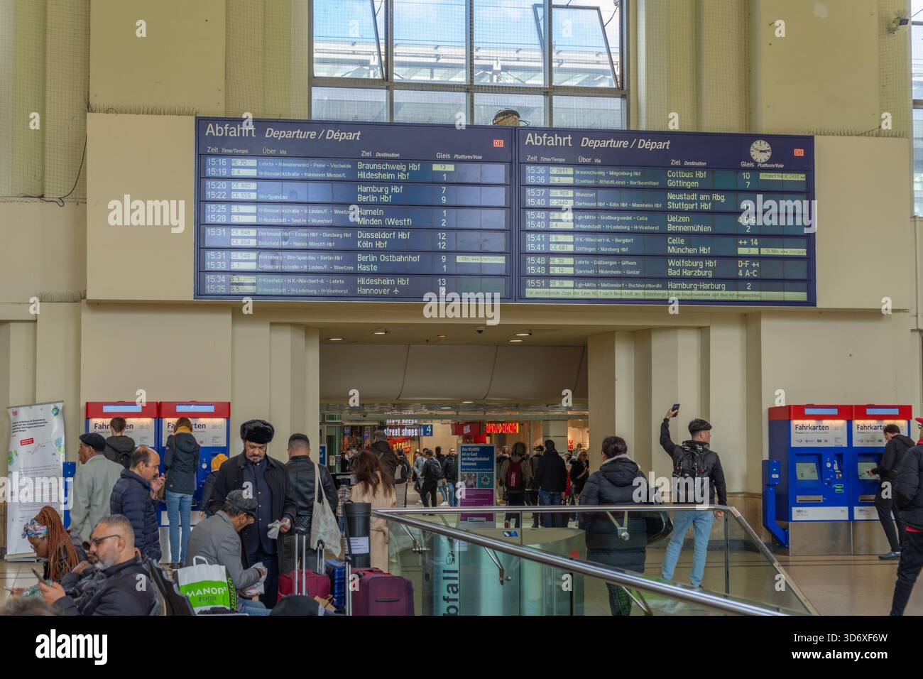 Abfahrtstafel und geschäftige Halle am Hannover Hauptbahnhof mit Abfahrt und Kartenautomaten. Stockfoto