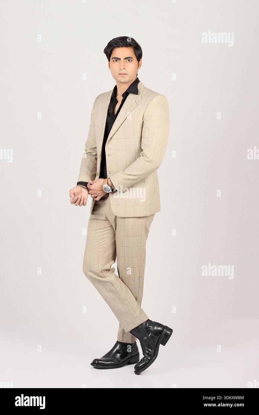 Porträt eines jungen, stilvollen Mannes in beigefarbenem Blazer mit schwarzem Hemd vor weißem Hintergrund voller Höhe Stockfoto