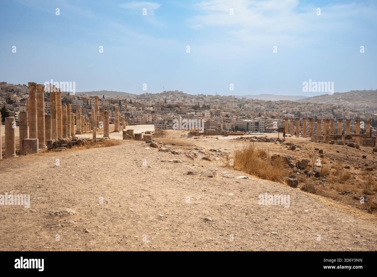 Jerash, Jordanien - 22. Oktober 2023: Römische Architektur mit Stadt im Hintergrund im Nahen Osten. Säulen und Städte während des Sonnentages in Gerasa. Stockfoto