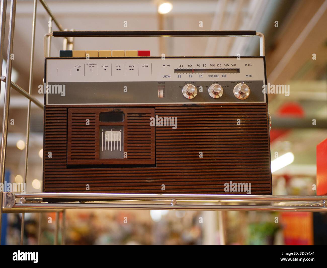 Tragbarer Vintage-Radioempfänger mit Kassettenspieler auf Metallregal, Retro-Audiogeräte aus den 1970er und 1980er Jahren Stockfoto