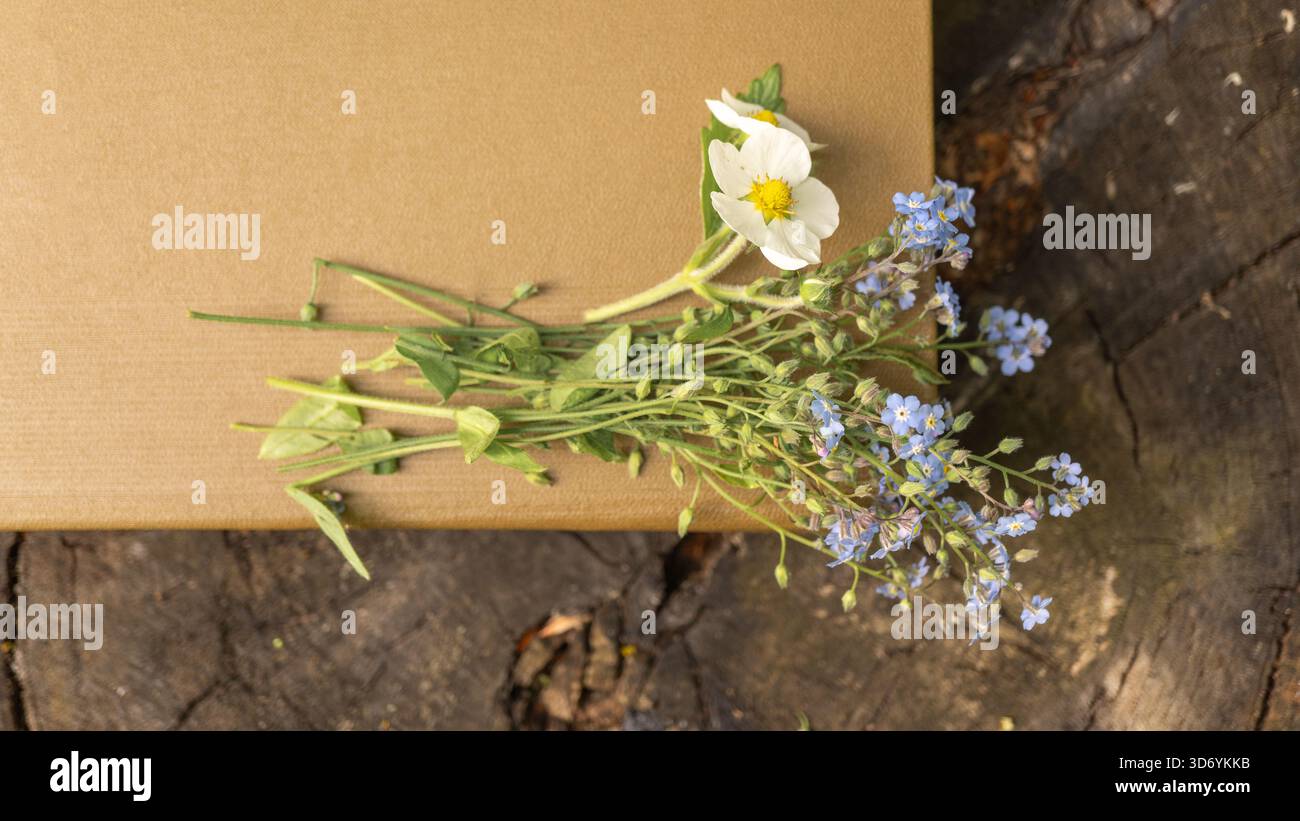 Wildblumen auf brauner Geschenkbox auf rustikaler Holzoberfläche Stockfoto