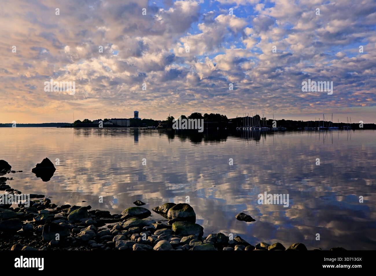 Ruhiger schöner Sommermorgen am Meer mit den Inseln Särkkä und Suomelinna am Horizont und Wolken, die sich auf der Wasseroberfläche spiegeln. Stockfoto
