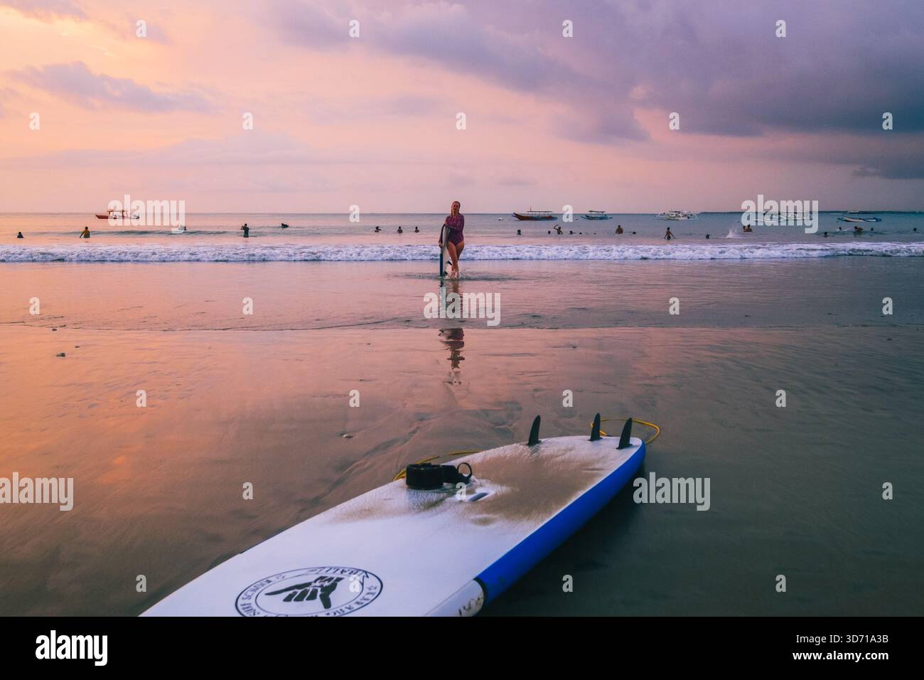 Surfer machen einen gemütlichen Spaziergang am Jimbaran Beach am Nachmittag, dem 5. Oktober 2025, in Bali, Indonesien Stockfoto