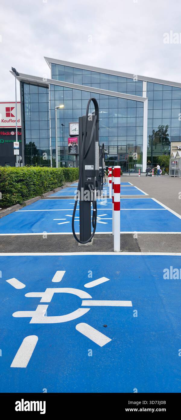Berlin - 28. Juni 2025: Das Ladegerät für Elektrofahrzeuge befindet sich vor einem modernen Glasgebäude. - Smartphone-aufgenommenes Stockfoto