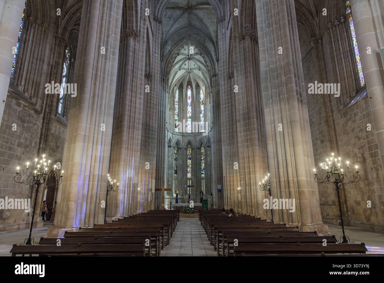 Das riesige Hochgewölbe des Klosters Batalha in Portugal. Hölzerne Bänke führen in Richtung Altar unter herrlicher gotischer Architektur. Stockfoto