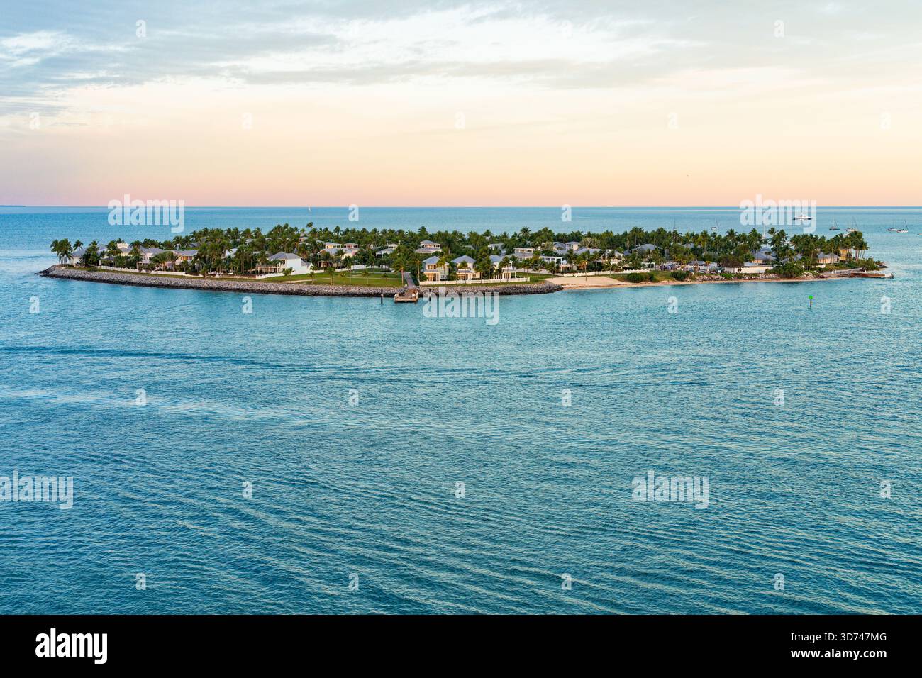 Blick auf den Sonnenaufgang auf Sunset Key in der Nähe von Key West in den Florida Keys, mit türkisfarbenem Wasser und Häusern am Wasser. Stockfoto