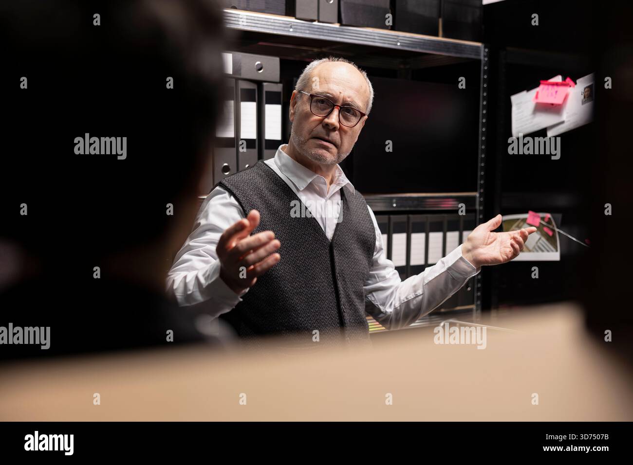 Kommissar und Assistentin, die Ermittlungen in der Detektivarbeit einleiten, archivierte Akten und Überwachungsfotos überprüfen, um wichtige Beweise gegen organisierte Kriminalität zu sammeln. Stockfoto