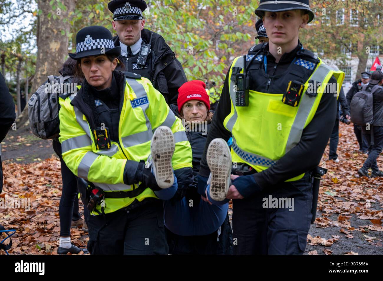 Eine Frau wird verhaftet und von der Polizei getragen, weil sie ein Schild trägt: „Ich bin gegen Völkermord, ich unterstütze die Palästinensische Aktion“. Heben Sie den Verbot-Protest auf, London. Stockfoto