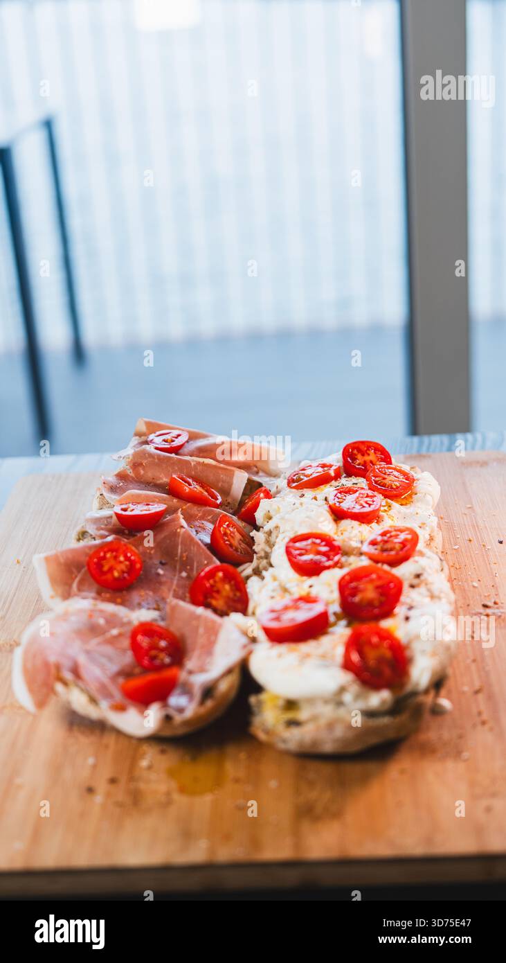 Italienisches Baguette mit cremiger Burrata, Schinken, Kirschtomaten, Olivenöl und Kräutern. Ein einfaches, elegantes, italienisch inspiriertes Mittagessen oder Vorspeise, frisch Stockfoto