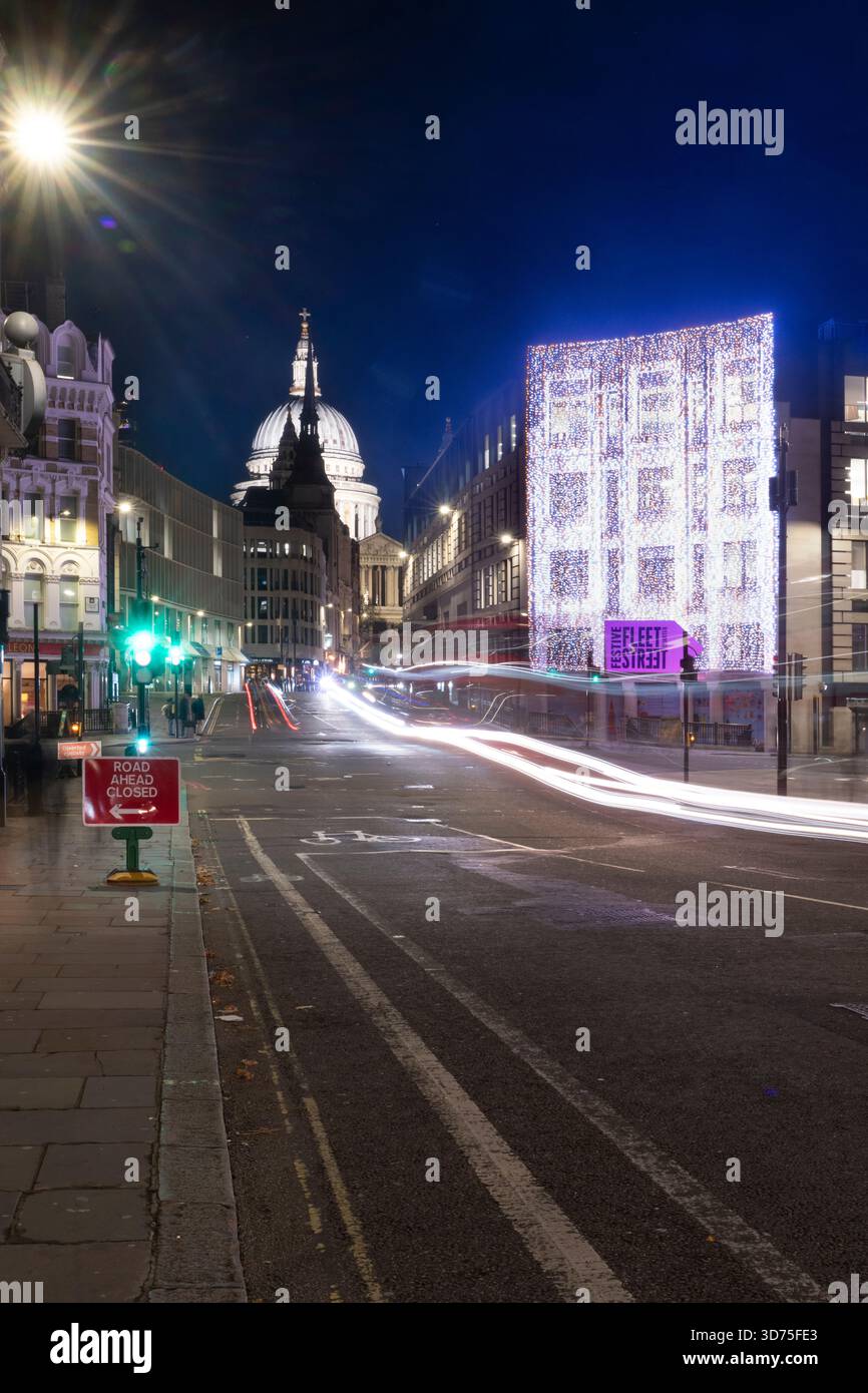 Nacht auf der Fleet Street, London, mit St. Paul's Cathedral im Hintergrund. Verkehrsampeln und festliche Lichter beleuchten die Straße. Stockfoto