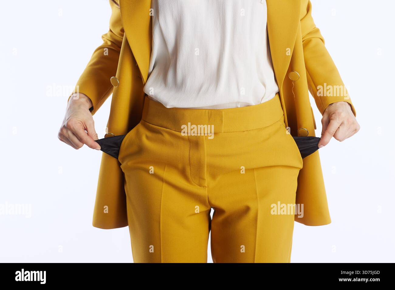 Eine Nahaufnahme einer Person in einem senfgelben Business-Anzug, die leere Taschen herauszieht, die auf mächtige Weise finanzielle Schwierigkeiten, Schulden oder Fu-Mangel symbolisiert Stockfoto