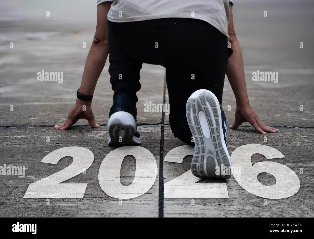 Athlet in Startposition auf der Strecke mit großem Text von 2026, der Neuanfänge, persönliche Ziele, Ehrgeiz, Motivation und Zukunftsplanung symbolisiert. Ideal Stockfoto