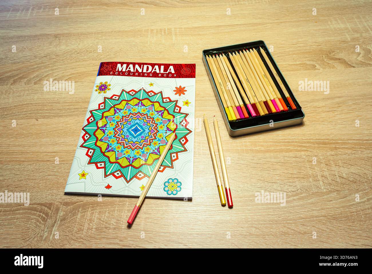 Mandala Malbuch mit Bleistiften auf Holztisch zur kreativen Entspannung. Stockfoto