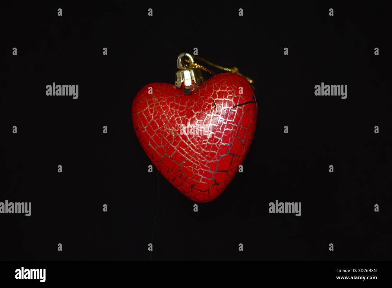 Rotes Herz-Ornament mit rissigem Muster, isoliert auf schwarzem Hintergrund. Stockfoto