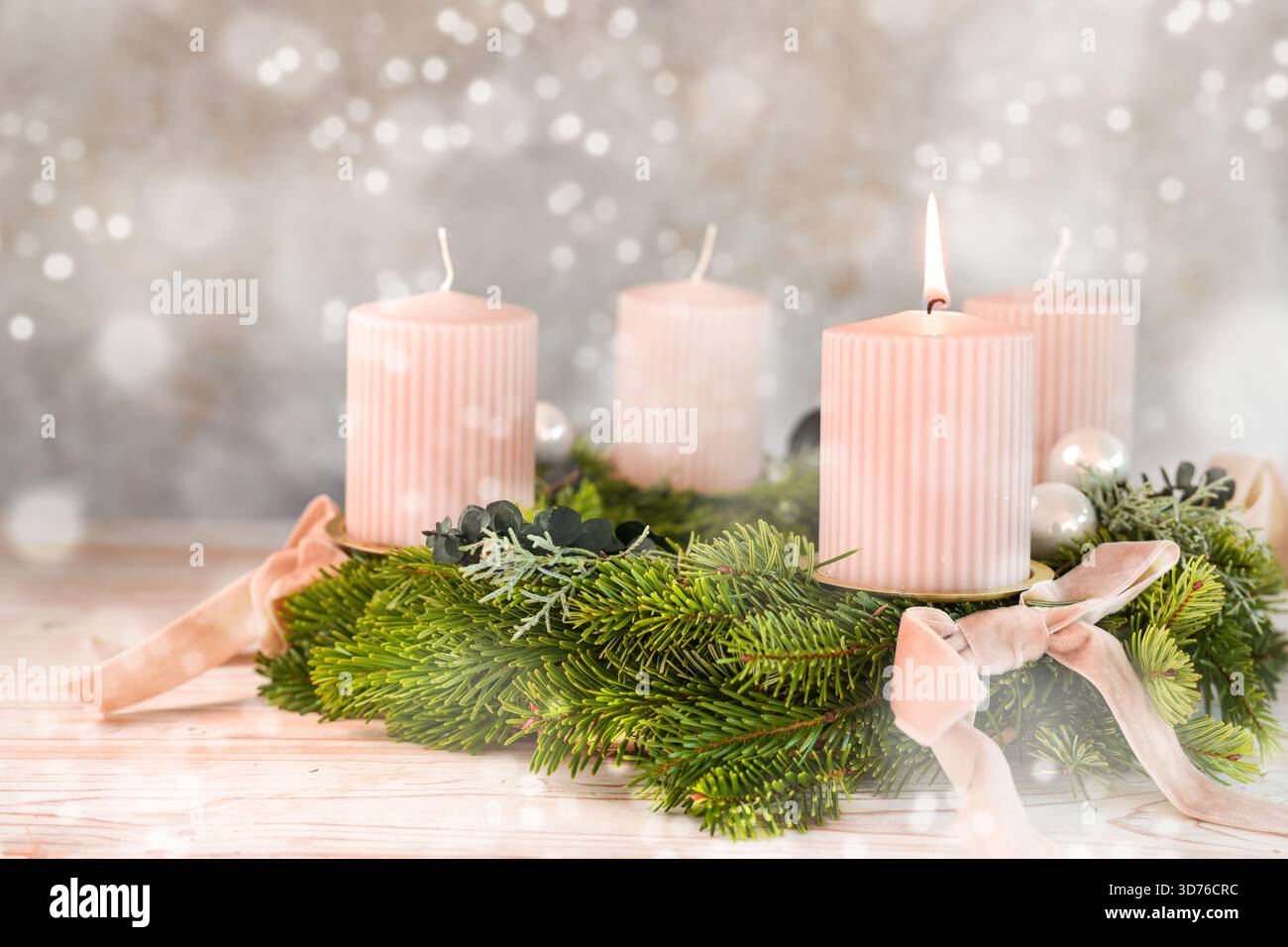 Erster Adventssonntag, vier blassrosa Kerzen auf einem Adventskranz, eine davon beleuchtet, schneebedeckter Bokeh-Hintergrund, feminine Weihnachtsdekoration, Kopierraum Stockfoto